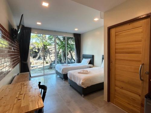 乌泰他尼府Uthaithani Resort的一间卧室设有两张床、一张桌子和一个窗口