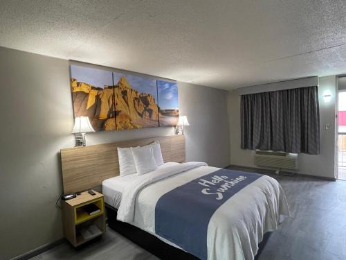 萨利纳南萨利纳戴斯酒店的酒店客房设有一张床,墙上挂有绘画作品