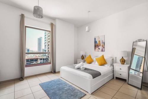 迪拜Sunkissed holiday homes 2 and 4 BR Apartments on JBR beach near mall & metro & bluewaters Island的白色的卧室设有床和窗户