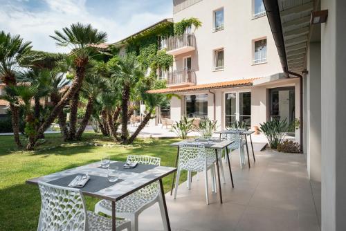 马西亚娜马里纳Marina Garden Hotel的一个带桌椅的庭院,棕榈树