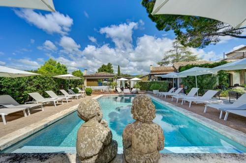 卢马罕Hotel Bastide & SPA - Villa de Lourmarin的别墅前方设有一座带两座雕像的游泳池