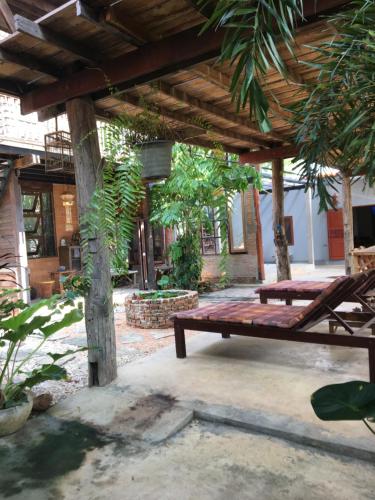 南邦Baan Mali Lampang Homestay的庭院内带长凳的木凉亭