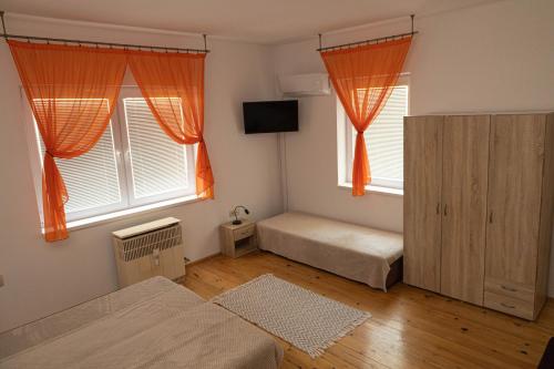 ObidVínny dom - Rumcajz - Borház的一间卧室设有两张床和两个窗户,窗户配有橙色窗帘