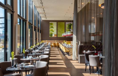 慕尼黑慕尼黑里奥纳多皇家酒店的餐厅设有桌椅和大窗户。