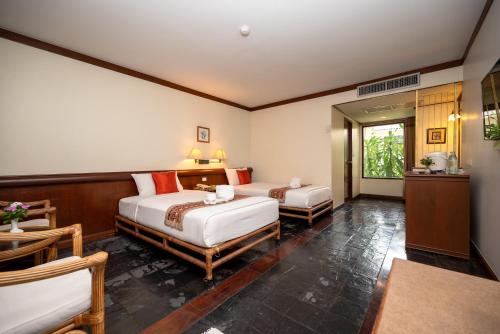 北碧Comsaed River Kwai Resort SHA的一间卧室配有两张床和一张桌子及椅子