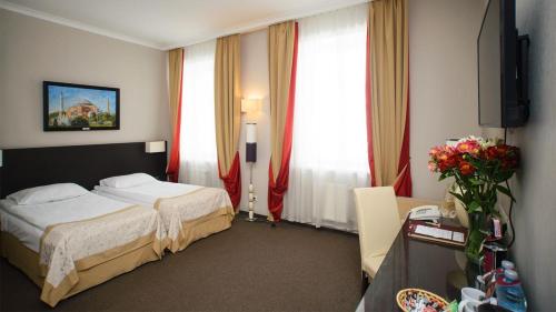 哈尔科夫Optima Collection Kharkiv Hotel的酒店客房设有一张床和两个窗户。
