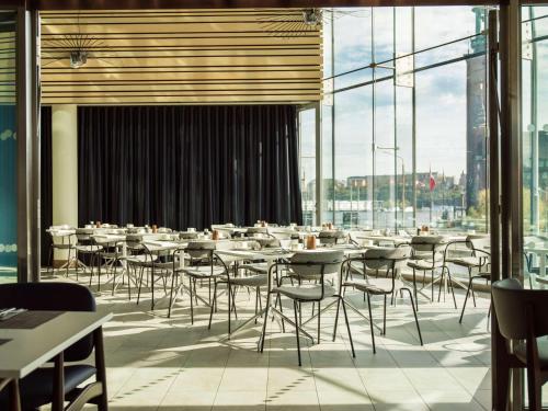 斯德哥尔摩斯德哥尔摩水滨丽笙酒店的餐厅设有桌椅和大窗户。