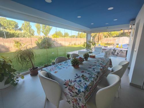 AlgeteCasa de sol, piscina y jacuzzi con 4 hab en Comunidad de Madrid的一间带长桌和白色椅子的用餐室