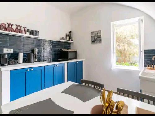 多尔切阿夸Casa Eva的厨房配有蓝色橱柜、桌子和窗户。