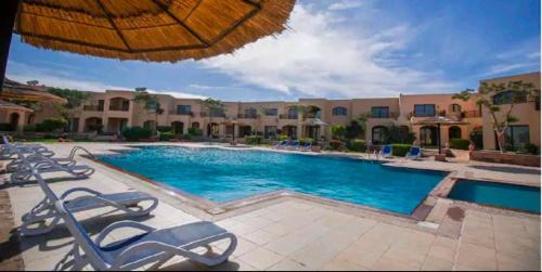 赫尔格达Prime Home The View Hurghada的一个带椅子和遮阳伞的大型游泳池