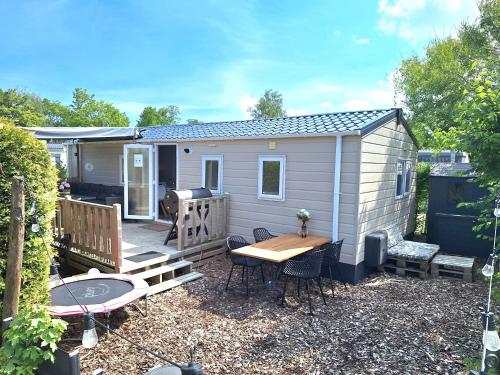 劳雷尔苏格EnJoy Meer und See Ferienhaus -Aan het Lauwersmeer in Lauwersoog -3 Slaapkamers - 1 tot 6 pers -Vanaf 14u al inchecken! Free WIFI!的天井上的小棚子配有桌椅