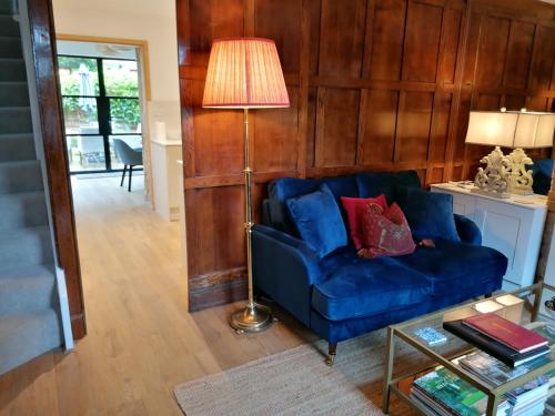 奇平卡姆登Merriman Cottage的客厅配有蓝色的沙发和灯具