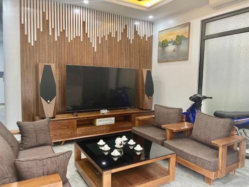 Green Bay Luxury Villa Sonasea Vân Đồn的客厅配有大电视、椅子和桌子