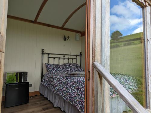 TrefeglwysTop of the Rock Glamping的一个小房间的一个床位,设有窗户