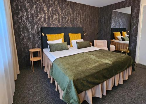 豪基普达斯Samantta Hotel & Restaurant的一间卧室配有一张带黄色和绿色床单的大床