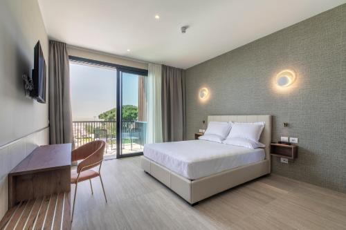 利多迪耶索罗Hotel Gallia & Resort的一间带一张床和一张书桌的卧室以及一个阳台