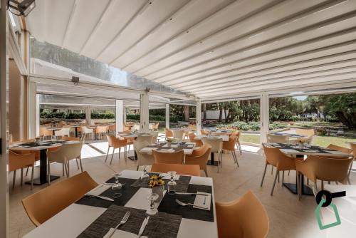拉科纳HOTIDAY Hotel Isola D'Elba的餐厅设有桌椅和大窗户。
