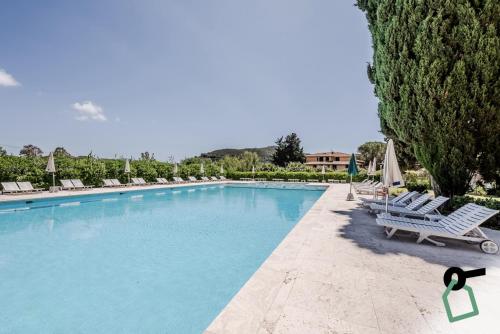 拉科纳HOTIDAY Hotel Isola D'Elba的一个带躺椅和树木的大型游泳池