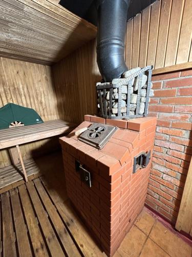 维尔纽斯Trijų žvaigždučių palapinė Vilniuje的一个带长凳的房间内的砖炉