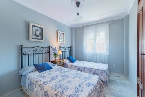 奇克拉纳－德拉弗龙特拉Ático en Novo Sancti Petri的卧室设有两张床铺和蓝色的墙壁