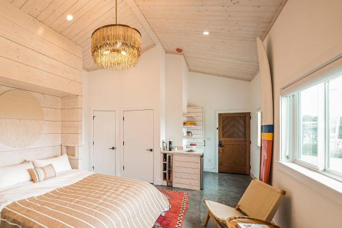 斯廷森海滩Funboard Room includes King Bed and Mini Kitchenette的一间卧室配有一张床、一把椅子和一个吊灯。
