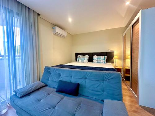 圣保罗Flat Bienal Ibirapuera c/ Sacada UH 1107的一间卧室配有一张床和一张蓝色的沙发