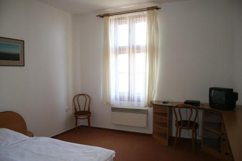 施滕贝克Penzion Na Kiosku的一间卧室配有一张床、一张书桌和一个窗户。