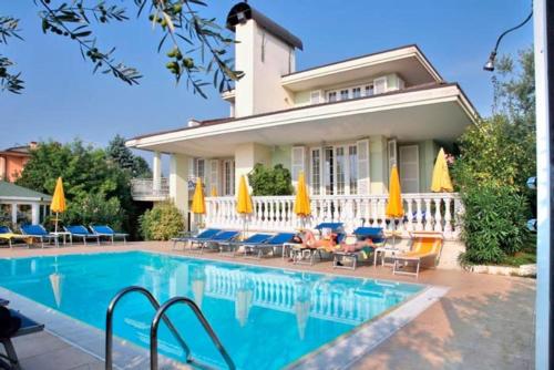 巴多利诺Hotel GARDENIA & Villa CHARME Adults Friendly 10Plus的一座房子,设有一座带椅子和遮阳伞的游泳池