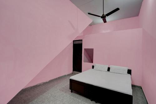 诺伊达OYO Hotel star palace的粉红色的卧室配有床和吊扇