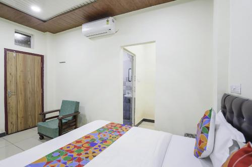 赖布尔FabExpress Sai Palace的一间卧室配有一张床和一把绿色椅子