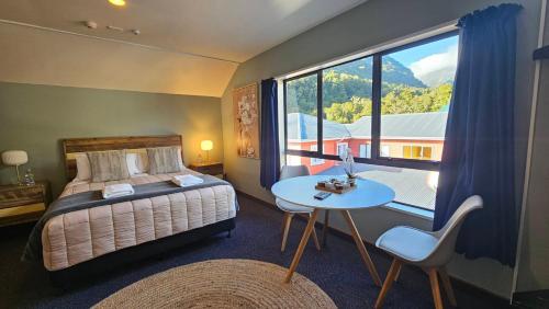 弗朗兹约瑟夫Franz Josef Montrose Lodge的一间卧室配有一张床、一张桌子和一个大窗户