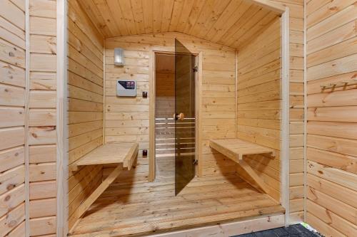 卡尔维亚Domki i pokoje Angelo z sauną i jacuzzi- Karwia的木制桑拿房,设有两个长椅和门