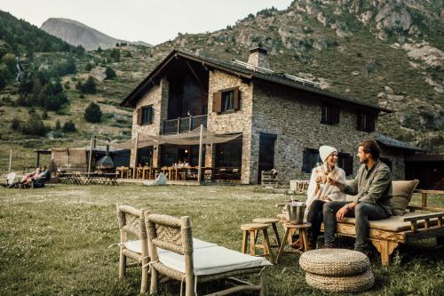 卡尼略L´Ovella Negra Mountain Lodge的两个人坐在房子前面的长凳上