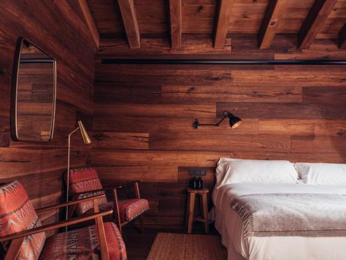 卡尼略L´Ovella Negra Mountain Lodge的卧室设有木墙和一张床及椅子