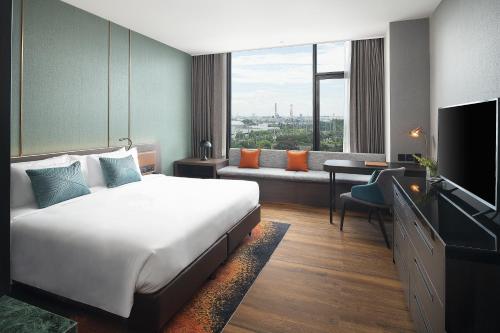 春武里Hotel Nikko Amata City Chonburi的酒店客房配有床、沙发和电视。
