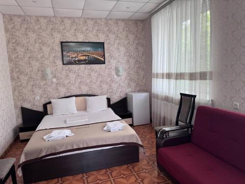 VoznesenskMotel Xameleon的酒店客房,配有一张床和一张红色的沙发