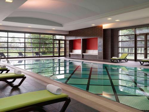 特拉布宗特拉布宗诺富特酒店的一个带绿色椅子和窗户的大型游泳池