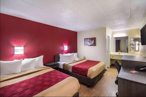 查尔斯顿Super 8 by Wyndham Charleston WV的酒店客房设有两张床和红色的墙壁。