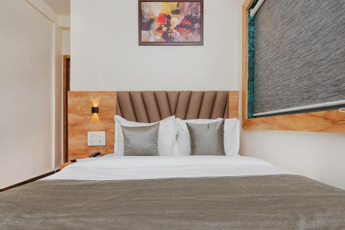 孟买FabHotel Airport Palace的卧室配有一张带白色床单和枕头的大床。