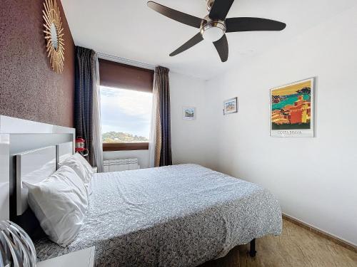 滨海托萨LETS HOLIDAYS SEA VIEWS APARTMENT & POOL in SA GABARRA的一间卧室配有一张床和吊扇