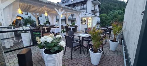 卡尔帕奇Hotel Kolorowa的庭院里设有桌子和植物,花瓶上是白色的花瓶