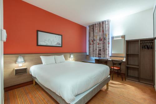 DéolsAce Hotel Chateauroux Déols的酒店客房设有一张大床和一张书桌。