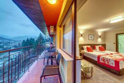 斯莫梁基帕丽斯阿尔法酒店的带阳台的酒店客房,配有一张床铺和一张桌子