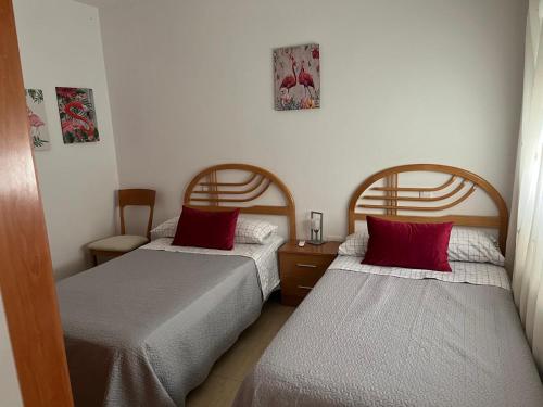 曼萨纳雷斯Jesús Del Perdón的客房内的两张床和红色枕头