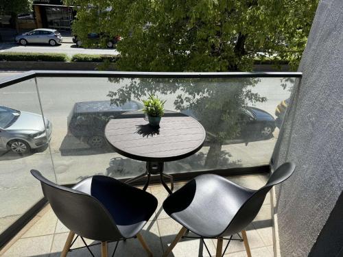 奥赫里德Paradiso Apartments的阳台上的桌子、两把椅子和盆栽植物