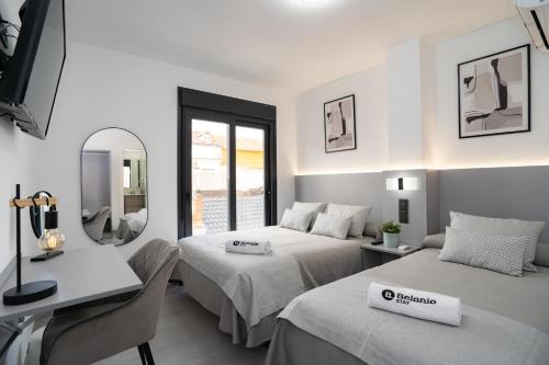 马拉加Stay Belonio的一间卧室配有两张床、一张桌子和一面镜子