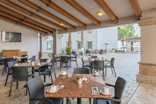 萨尔蒂约voco Saltillo Suites, an IHG Hotel的一间带桌椅的餐厅和庭院