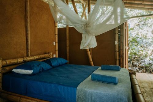 伯里塔卡Finca La Selvita的一间卧室配有一张带蓝色床单的床和一扇窗户。