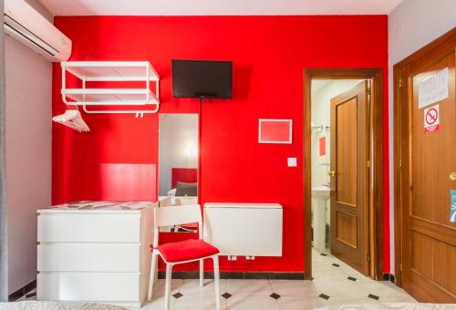 阿尔姆尼卡Hostal Tropical的红色的房间,有红色的墙壁和红色的椅子