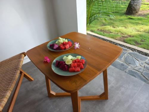 巴图卡拉Rumah Markisa Batukaras的木桌旁的两盘水果